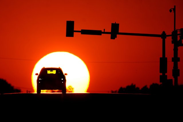 A motorist is silhouetted against the setting sun on the summer solstice Thursday, June 20, 2024, in Raytown, Mo. The summer solstice marks the longest day of the year in the northern hemisphere. (Photo by Charlie Riedel/AP Photo)