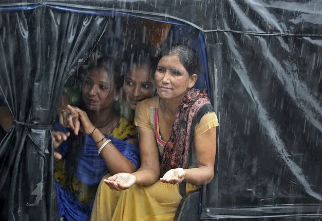 Commuters look-out from an auto-rickshaw during a heavy rain shower in Chandigarh, India, July 20, 2015. Good rainfall this year is key to boosting a rural economy hit by delayed and lower rains last year, as well as keeping a lid on food inflation and giving India's central bank more scope to cut lending rates. (Photo by Ajay Verma/Reuters)