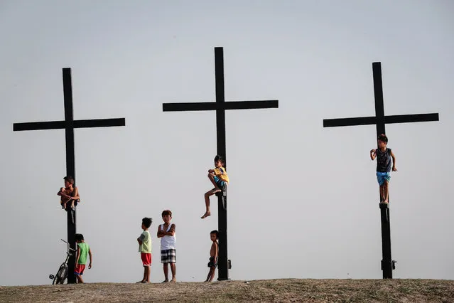 Filipino children play along the site of the re-enactment of the crucifixion of Jesus Christ on Holy Wednesday, San Pedro Cutud village, San Fernando city, north of Manila, Philippines, 12 April 2017. On Good Friday more than 40,000 tourists and devotees are expected to visit San Fernando, Pampanga to witness the crucifixion rites in Pampanga in observance of the Holy Week. (Photo by Mark R. Cristino/EPA)