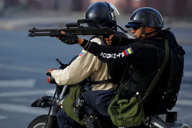 A riot security force member aims his weapon toward demonstrators during a rally against Venezuela's President Nicolas Maduro's government in Caracas, Venezuela, June 26, 2017. (Photo by Christian Veron/Reuters)