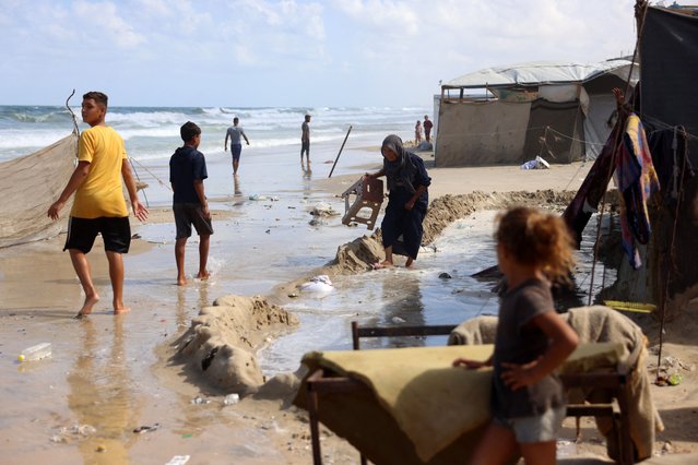 Displaced Palestinians gather near tents that were flooded with sea water because of the high tide combined with windy weather, along the shore of Khan Yunis in the southern Gaza Strip on September 15, 2024, amid the ongoing war between Israel and the Hamas militant group. (Photo by Bashar Taleb/AFP Photo)