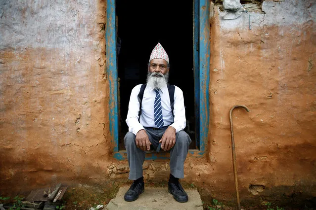 Durga Kami, 68, who is studying tenth grade at Shree Kala Bhairab Higher Secondary School, poses for a picture wearing his school uniform at the door of his one-room house in Syangja, Nepal, June 5, 2016. (Photo by Navesh Chitrakar/Reuters)