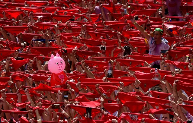 A pig-shape balloon is held up among participants holding red scarves as they celebrate the “Chupinazo” (start rocket) to mark the kickoff at noon sharp of the San Fermin Festival, in front of the Town Hall of Pamplona, northern Spain, on July 6, 2017. (Photo by Miguel Riopa/AFP Photo)