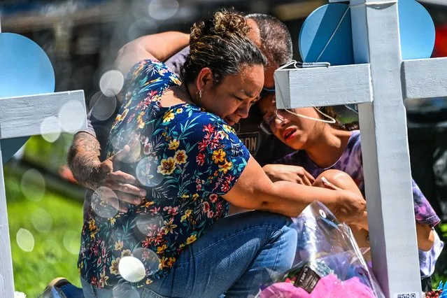 People mourn at a makeshift memorial outside Uvalde County Courthouse in Uvalde, Texas, on May 26, 2022. Texas police faced angry questions May 26, 2022 over why it took an hour to neutralize the gunman who murdered 19 small children and two teachers in Uvalde, as video emerged of desperate parents begging officers to storm the school. (Photo by Chandan Khanna/AFP Photo)