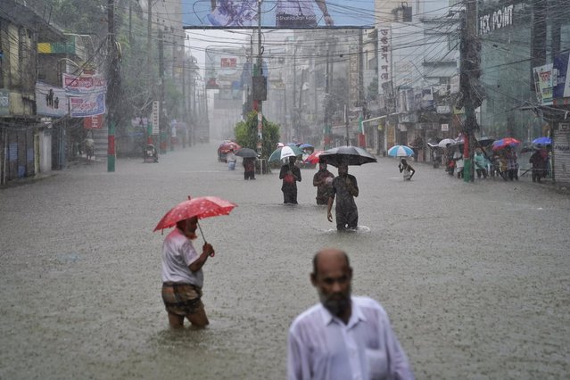 People navigate a flooded street following incessant rains in Feni, a coastal district in southeast Bangladesh bordering with Indian Tripura state, Bangladesh, Thursday, August 22, 2024. (Photo by AP Photo)