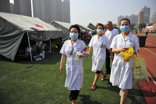 Medical volunteers walk past tents set up at the playground of a primary school as temporary shelters for victims after explosions at Binhai new district in Tianjin, China, August 13, 2015. (Photo by Reuters/Stringer)