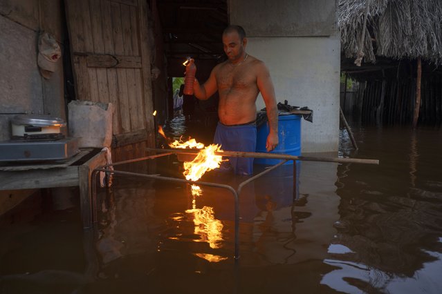 A man lights charcoal to cook dinner in his flooded home after the passage of Hurricane Helene in Guanimar, Artemisa province, Cuba, September 25, 2024. (Photo by Ramon Espinosa/AP Photo)