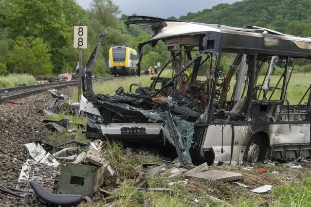Rescue workers stand by a burned-out bus in Baden-Wuerttemberg on May 24, 2022. This bus came to a standstill on a railroad crossing during a traffic jam and was hit by a train. The bus burned out, numerous people were injured. (Photo by Stefan Puchner/dpa)