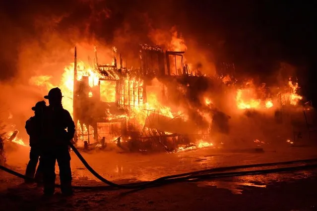 Fire engulfs a seniors residence in L'Isle-Verte, Que., early Thursday, Jan.23, 2014. A multimillion-dollar lawsuit has been filed against the Quebec town where 32 people died in a fire at a seniors' home last January. (Photo by Frances Drouin/The Canadian Press)