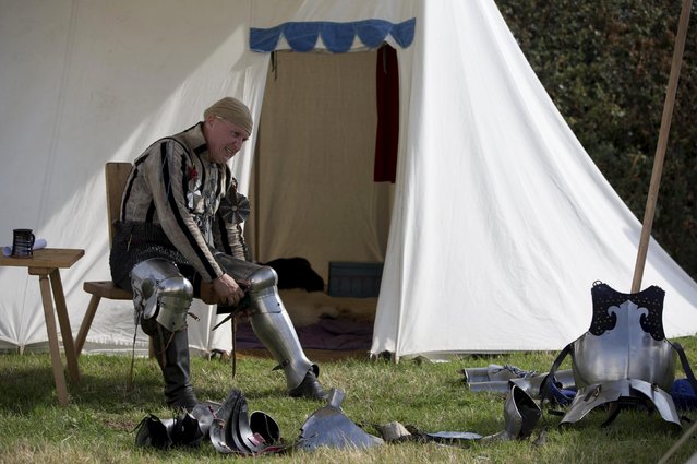 A historical re-enactor in a living history camp prepares his costume as he takes part in an anniversary event for the Battle of Bosworth near Market Bosworth in central Britain August 22, 2015. (Photo by Neil Hall/Reuters)