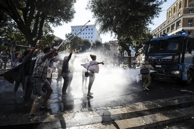 Italian law enforcement officers use water cannons to disperse migrants, in downtown Rome, Thursday, August 24, 2017. Protests erupted as police continued an operation to evict some 800 Eritrean and Ethiopian refugees from a building they have occupied since 2013, despite protests from the U.N. refugee agency, UNICEF, and humanitarian organizations. (Photo by Angelo Carconi/ANSA via AP Photo)