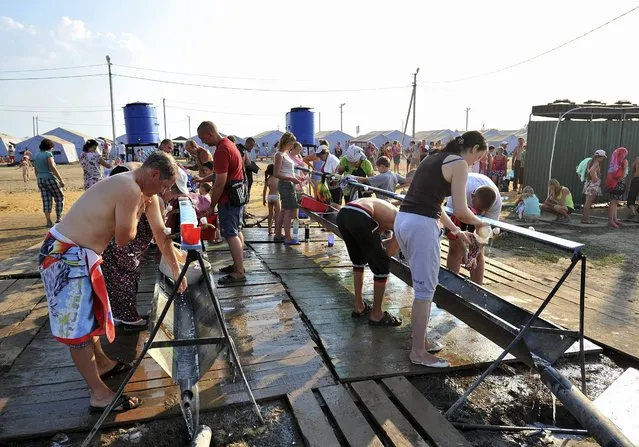 Refugees from Eastern Ukraine wash themselves at a refugee temporary tent camp at the Donetsk city of Rostov area, Russia, 08 August 2014. At least 19 people were killed and 97 injured in fighting between government troops and pro-Russian separatists in eastern Ukraine over the past 24 hours, officials said. (Photo by Arkady Budnitsky/EPA)
