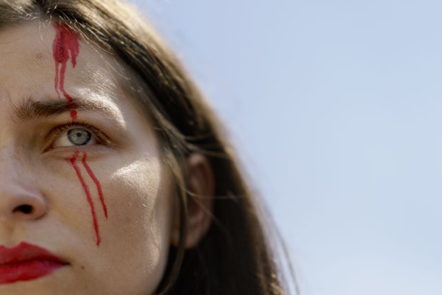Olha Maliuchenko, the fiancé of a Ukrainian soldier from the Azov Regiment who was captured by Russia in May after the fall of Mariupol, wears paint depicting blood on her face during a rally in Kyiv, Ukraine, Saturday, July 30, 2022. The rally comes a day after Russian and Ukrainian officials blamed each other for the deaths of dozens of Ukrainian prisoners of war in an attack Friday on a prison in a separatist-controlled area of eastern Ukraine. Maliuchenko has no information on the well-being of her fiancé. (Photo by David Goldman/AP Photo)
