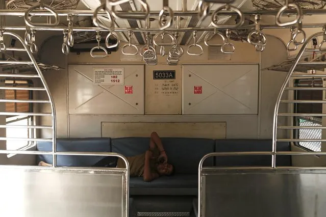 A railway employee talks on the phone inside an empty train compartment after railway services were shut down in Mumbai, India, March 23, 2020. (Photo by Francis Mascarenhas/Reuters)