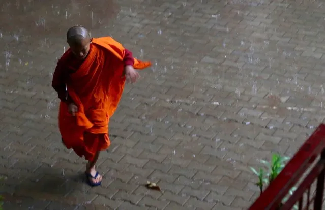An exiled Tibetan Buddhist monk runs to escape from rain during a special prayer meeting on the occasion of “Guru Purnima” in Bangalore, India, 19 July 2016. Guru Purnima is a festival traditionally celebrated by Hindus and Buddhists during the full moon day in the Hindu month of Ashad (July-August). (Photo by Jagadeesh N.V./EPA)