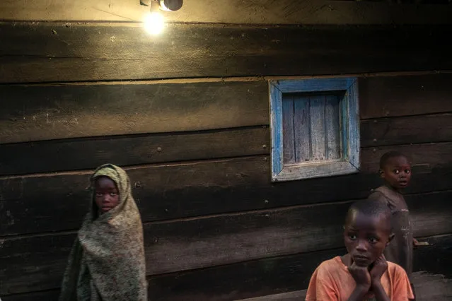 Children stand outside a house connected to a electric grid in Bugara on July 17, 2016. The vast majority of the Congolese population doesn't have access to electricity, and the small portion of the inhabitants that are connected to the grid are suffering frequent and long breakdowns. In the case of the village of Bugara, electricity is produced by the dam of Matebe, a project from the Virunga Alliance for a sustainable development in the surroundings of the Virunga National Park. (Photo by Eduardo Soteras/AFP Photo)