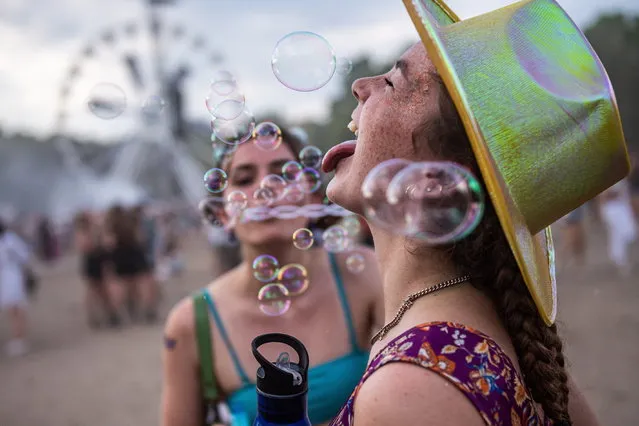 Festival goers blow soap-bubbles at the 28th Sziget (Island) Festival on Shipyard Island, Northern Budapest, Hungary, 15 August 2022. The festival is one of the biggest cultural events of Europe offering art exhibitions, theatrical and circus performances and above all music concerts. (Photo by Marton Monus/EPA/EFE)