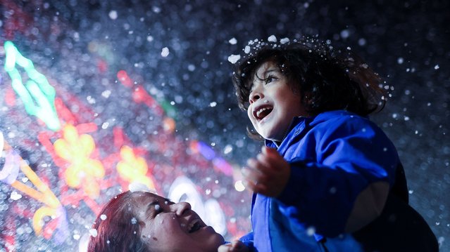 A boy plays with soap suds simulating snowfall at Zocalo Square as part of Christmas celebrations in Mexico City, Mexico on December 17, 2024. (Photo by Raquel Cunha/Reuters)