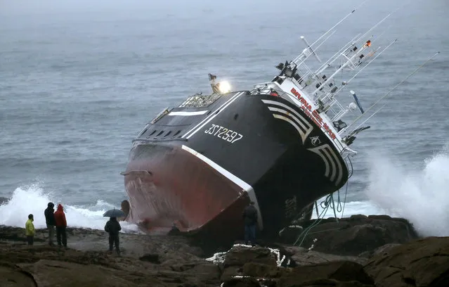Several people look at the fishing ship 'Divina del Mar' after it run aground near Castro de Barona, in the town of Porto do Son, Galicia, northwestern Spain, 12 November 2019. One of the crew members died after he jumped from the ship during the accident. Strong winds and heavy rainfalls hit the region of Galicia in recent days. (Photo by Lavandeira Jr./EPA/EFE)