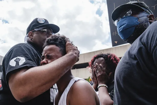Javon Williams, 13, is comforted by Rev. Jaland Finney, left, as he speaks during a march and rally for Jayland Walker, Sunday, July 3, 2022, in Akron, Ohio. Also pictured at center right is Lanette Williams, reacting after Javon's speech. Williams had just viewed the video released by police detailing the shooting death of Walker. (Photo by Andrew Dolph/Times Reporter via AP Photo)