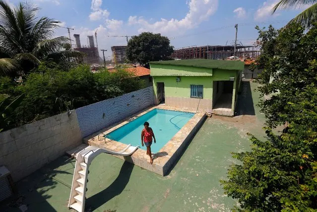 Marcia Lemos, 57, walks by a pool in her house, with cranes and construction work for the Rio 2016 Olympic Park seen in the background, at the Vila Autodromo slum in Rio de Janeiro, Brazil, January 28, 2015. (Photo by Ricardo Moraes/Reuters)