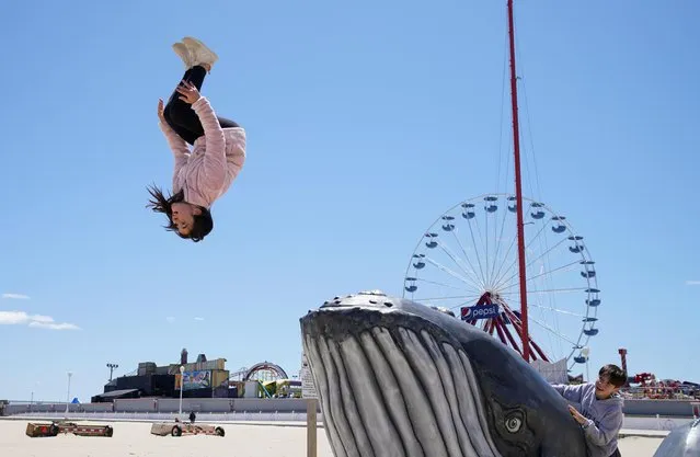 Eleni Kaliakoudas, 12, of Ocean City, leaps from a whale to perform a back tuck on the first day of eased coronavirus disease (COVID-19) restrictions in Ocean City, Maryland, U.S., May 9, 2020. (Photo by Kevin Lamarque/Reuters)