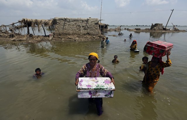 Women carry belongings salvaged from their flooded home after monsoon rains, in the Qambar Shahdadkot district of Sindh Province, of Pakistan, Tuesday, September 6, 2022. More than 1,300 people have been killed and millions have lost their homes in flooding caused by unusually heavy monsoon rains in Pakistan this year that many experts have blamed on climate change. (Photo by Fareed Khan/AP Photo)
