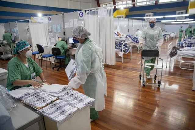 Health personnel work in a field hospital built inside a gym to treat COVID-19 patients in Santo Andre, on the outskirts of Sao Paulo, Brazil, Tuesday, June 9, 2020. (Photo by Andre Penner/AP Photo)