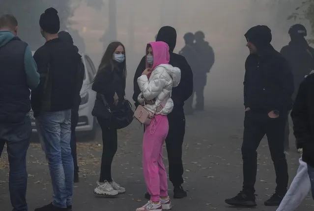 Local residents look on as smoke rises after a Russian drones strike, which local authorities consider to be Iranian made unmanned aerial vehicles (UAVs) Shahed-136, amid Russia's attack on Ukraine, in Kyiv, Ukraine on October 17, 2022. (Photo by Gleb Garanich/Reuters)