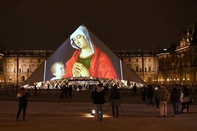 Images are projected onto the Louvre Pyramid in Paris at night on November 8, 2017 to mark the opening of the Louvre Abu Dhabi Museum on Saadiyat island in the Emirati capital.More than a decade in the making, the Louvre Abu Dhabi opened its doors on November 8, 2017. (Photo by Eric Feferberg/AFP Photo)