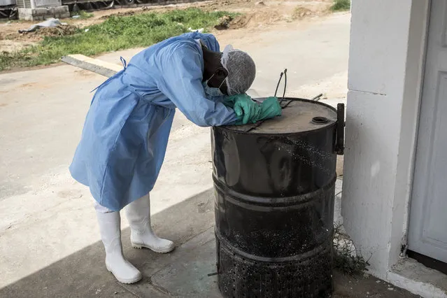 A hygienist rests as he waits outside a decontamination area in a COVID-19 coronavirus treatment centre that cares for positive patients that show little or no symptoms in Dakar on June 26, 2020. (Photo by John Wessels/AFP Photo)