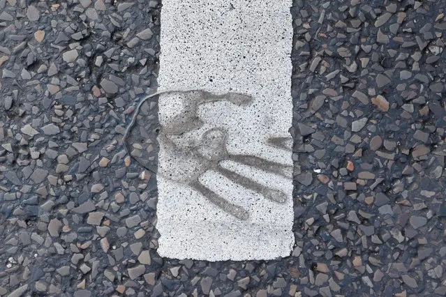 View of a handprint on the road after a climate activist's hand was unglued during a street blockade in Berlin, Germany on October 31, 2022. (Photo by Michele Tantussi/Reuters)