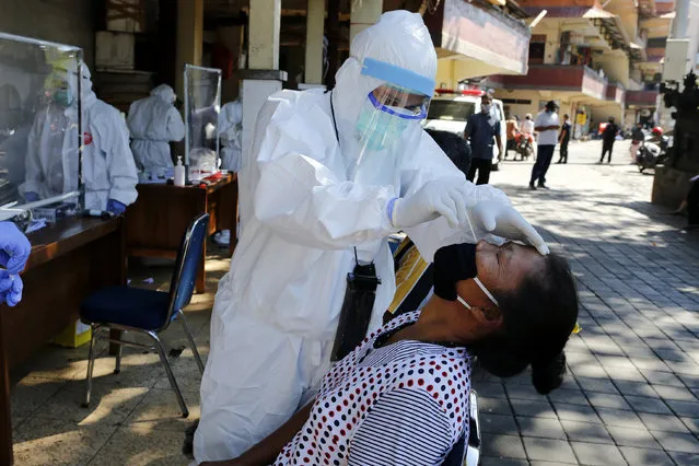 A heath worker takes a nasal swab sample during a public testing for the new coronavirus conducted at a market in Bali, Indonesia on Friday, June 12, 2020. (Photo by Firdia Lisnawati/AP Photo)