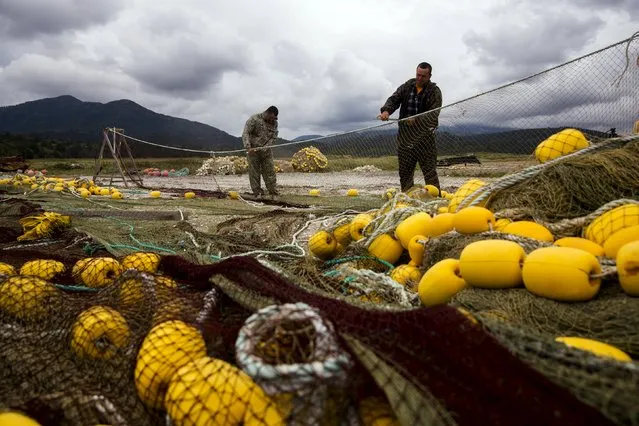 Fishermen repair nets on the shore of the Okhotsk Sea on the Southern Kurile island of Kunashir September 16, 2015. Russian residents of the island chain at the centre of a dispute between Japan and Russia that has held up a treaty to formally end World War Two hope a diplomatic solution will lure tourists and investment to help refurbish rickety infrastructure. The Southern Kuriles are referred to in Japan as the Northern Territories. (Photo by Thomas Peter/Reuters)
