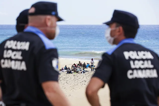 Would-be immigrants rest on Maspalomas beach next to policemen, on Gran Canaria in Spain's Canary Islands. (Photo by Borja Suarez/Reuters)
