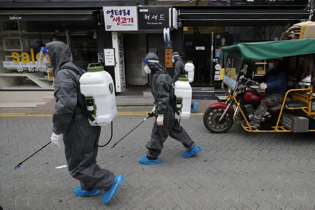 Health officials from the district office wearing protective gears disinfect as a precaution against the coronavirus as a man wearing a face mask rides a motorcycle in Incheon, South Korea, Thursday, September 17, 2020. (Photo by Lee Jin-man/AP Photo)