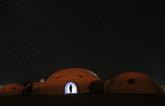 A picture taken on February 7, 2018 shows a member of the AMADEE-18 Mars simulation mission wearing a spacesuit standing in the doorway of a simulation habitat, with a view of the night sky above in Oman' s Dhofar desert, during an analog field simulation in a collaboration between the Austrian Space Forum and the Oman National Steering Comittee preparing for future human Mars missions. (Photo by Karim Sahib/AFP Photo)