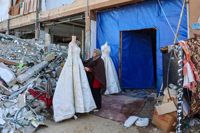 A Palestinian woman sells wedding dresses at a makeshift shop next to the rubble of destroyed buildings in Jabalia in the northern Gaza Strip on February 27, 2025, amid the ongoing truce between Israel and Hamas. (Photo by Omar Al-Qattaa/AFP Photo)