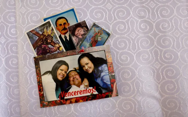 A postcard of Venezuela's President Hugo Chavez with his daughters; Maria Gabriela, left, and Rosa Virginia, is pinned together with prayer cards to the altar cloth in the military hospital's chapel, in Caracas, Venezuela, Tuesday, March 5, 2013. A brief statement read on national television by Communications Minister Ernesto Villegas late Monday carried the sobering news about the charismatic 58-year-old leader's deteriorating health. Villegas said Chavez is suffering from “a new, severe infection”. The state news agency identified it as respiratory. (Photo by Ariana Cubillos/AP Photo)