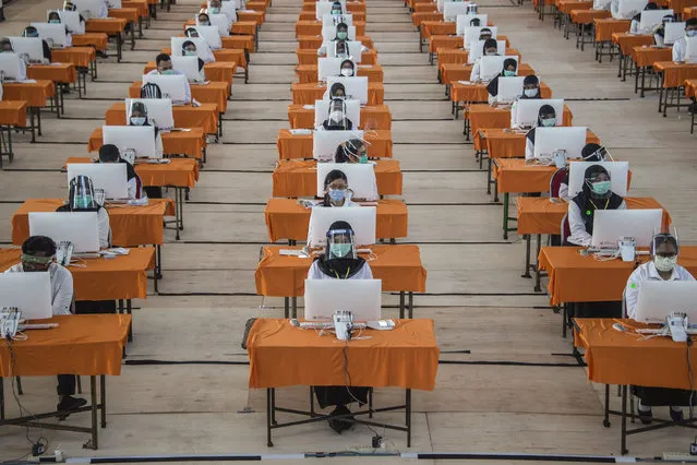 State civil employee candidates wearing face masks and shields as a precautionary measure against the spread of the COVID-19 coronavirus take a test in Surabaya on September 22, 2020. (Photo by Juni Kriswanto/AFP Photo)