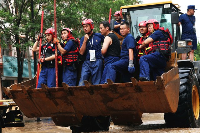 Rescue workers ride on a front loader as they make their way through a flooded road, after heavy rainfall in Miyun district of Beijing, China on July 29, 2025. (Photo by Florence Lo/Reuters)