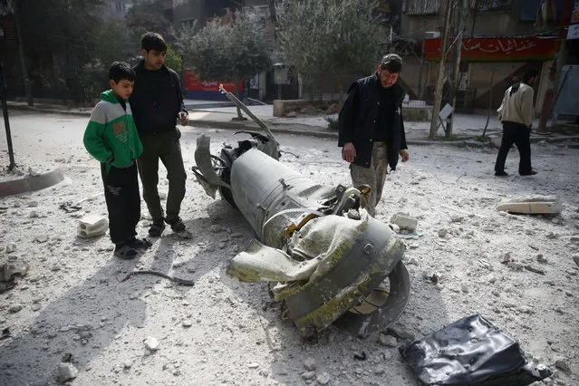 People inspect missile remains in the besieged town of Douma, in eastern Ghouta, in Damascus, Syria, February 23, 2018. (Photo by Bassam Khabieh/Reuters)