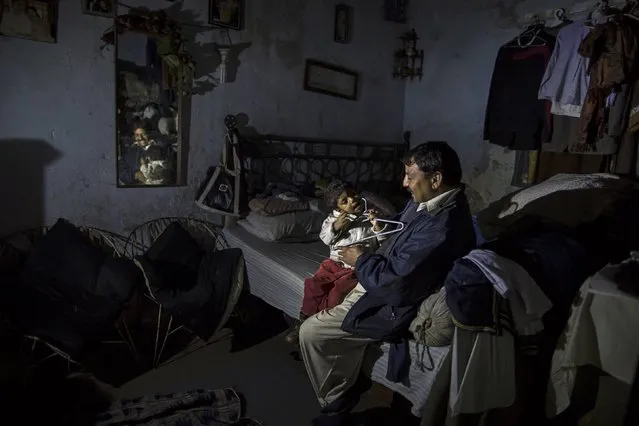 A man plays with his son as he sits at his one-room shack at a Christian slum in Islamabad December 4, 2014. (Photo by Zohra Bensemra/Reuters)