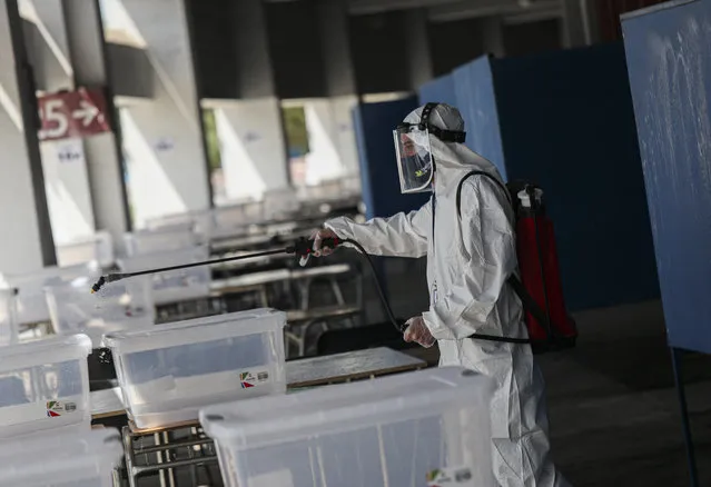 A worker disinfects an area of the National Stadium that will serve as a polling station for a constitutional plebiscite, in Santiago, Chile, Saturday, October 24, 2020, amid the COVID-19 pandemic. Chileans will decide on Sunday whether or not to replace the constitution that dates back to the dictatorship of Augusto Pinochet, and secondly, if the current Congress or other citizens should write the new text. (Photo by Esteban Felix/AP Photo)
