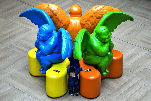 A child plays with himself in between the cupid statues on display inside a shopping mall in Beijing, Tuesday, February 28, 2023. (Photo by Andy Wong/AP Photo)