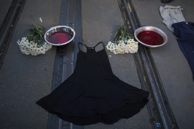 A dress is displayed on the street between flowers and bowls with a red liquid during a protest against the murder of councilwoman Marielle Franco in Rio de Janeiro, Brazil, Tuesday, March 20, 2018. Franco's murder came just a month after the government put the military in charge of security in Rio, which is experiencing a sharp spike in violence less than two years after hosting the 2016 Summer Olympics. (AP Photo/Leo Correa)