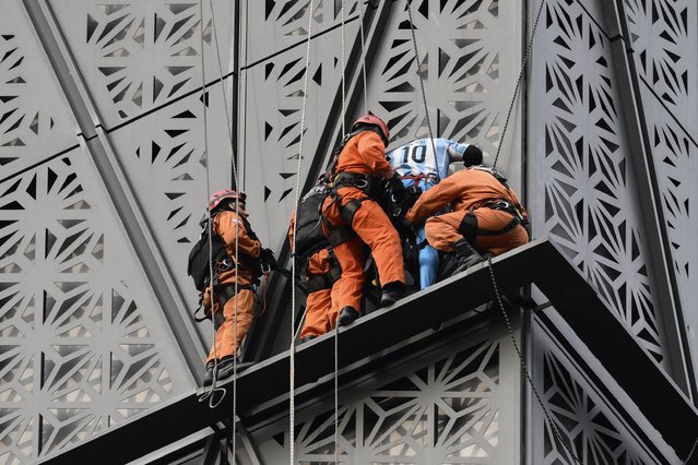 Firefighters intercept Polish climber Marcin Banot (2nd-R) as he climbed a building in Puerto Madero wearing an Argentina national football team jersey with Lionel Messi's number 10 in Buenos Aires on June 11, 2024. (Photo by Luis Robayo/AFP Photo)