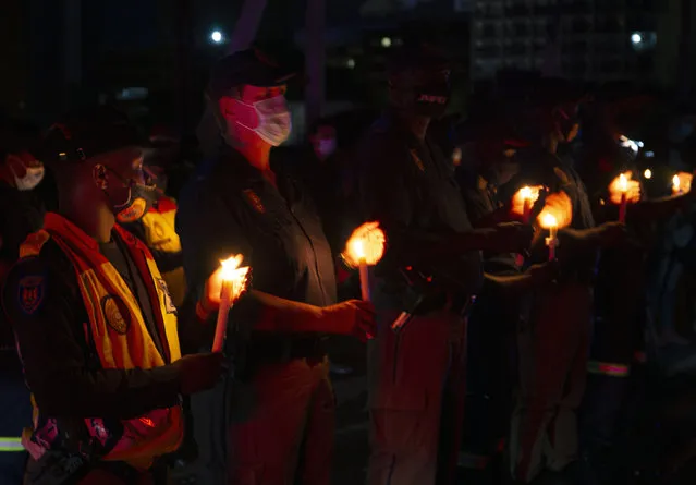 Frontline workers attend a candlelight ceremony on New Year's Eve on the famed Nelson Mandela Bridge in downtown Johannesburg Thursday, December 31, 2020. Many South Africans will swap firecrackers for candles to mark New Year's Eve amid COVID-19 restrictions including a nighttime curfew responding to President Cyril Ramaphosa's call to light a candle to honor those who have died in the COVID-19 pandemic and the health workers who are on the frontline of battling the disease. (Photo by Denis Farrell/AP Photo)