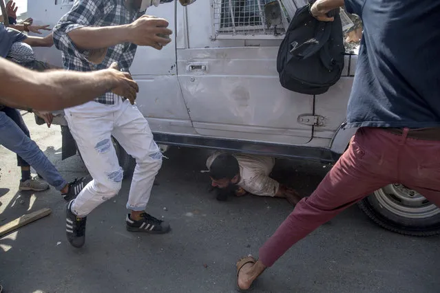 Kashmiri Protesters gather around an Indian paramilitary vehicle as it runs over a man during a protest in Srinagar, Indian controlled Kashmir, Friday, June 1, 2018. (Photo by Dar Yasin/AP Photo)