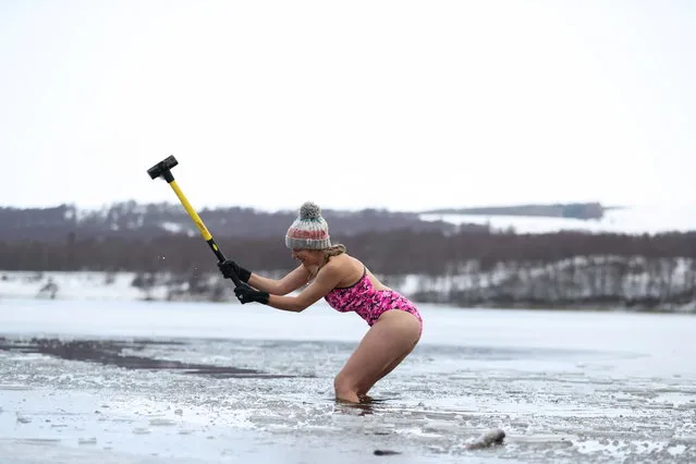 Nicky Goode uses sledgehammer to break the ice at Loch Insh, Scotland, Britain on December 30, 2020. (Photo by Russell Cheyne/Reuters)